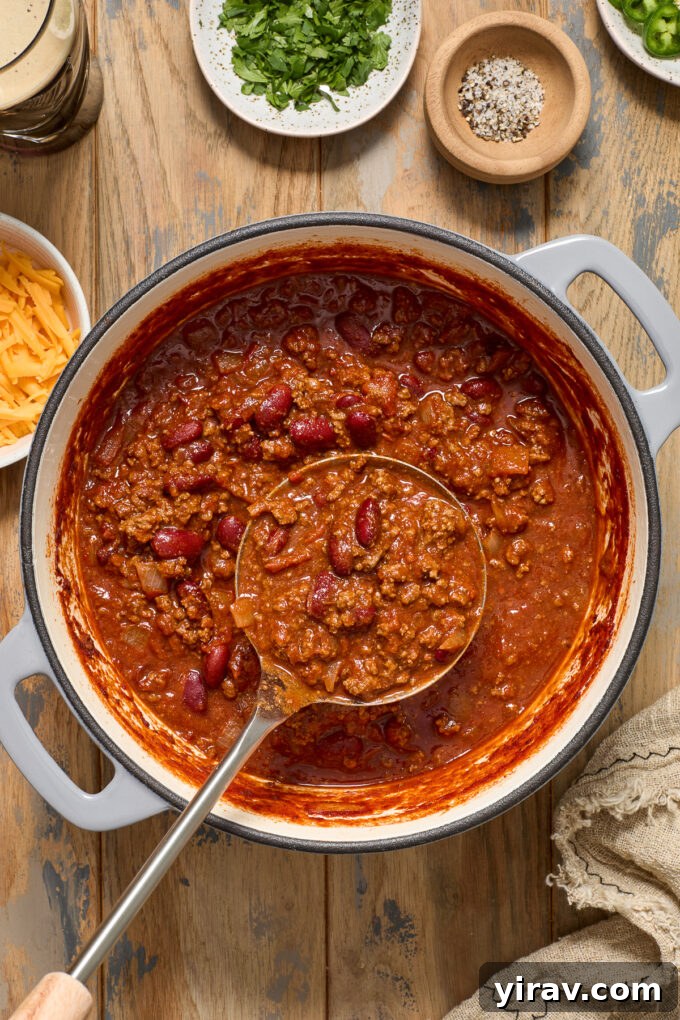 Rich Guinness Chili 3 Guinness stout chili simmering in a red Dutch oven with a ladle resting inside.