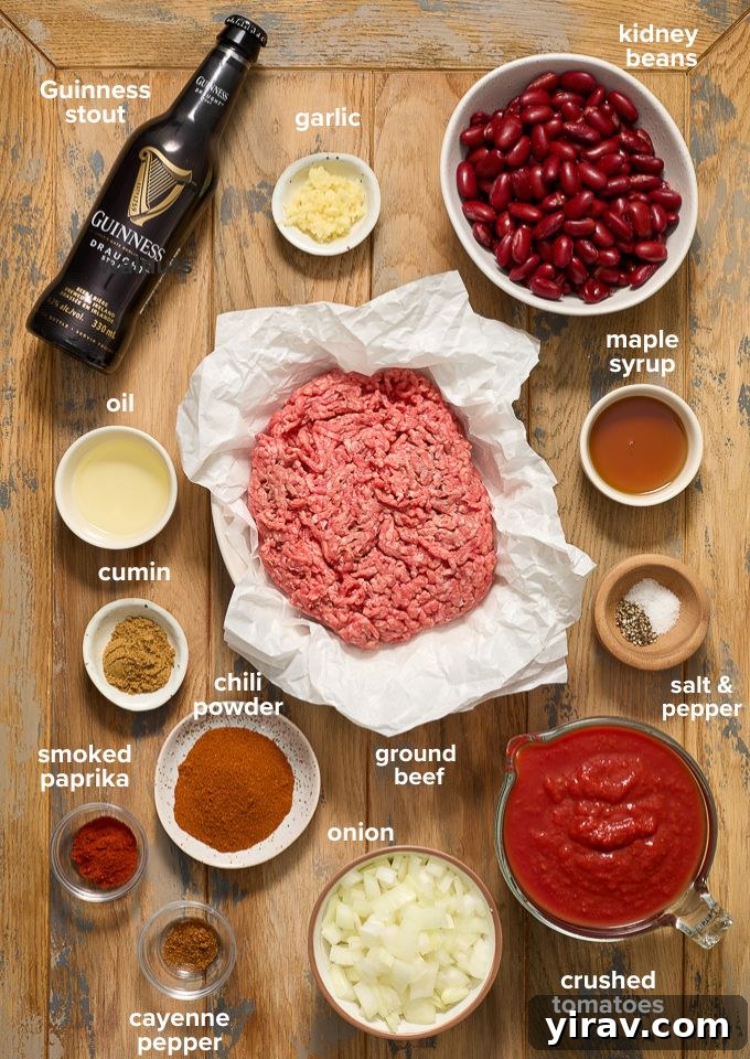 Rich Guinness Chili 4 Various ingredients for Guinness chili recipe, including ground beef, Guinness bottle, canned tomatoes, and spices, laid out on a table.