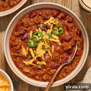 Guinness chili with ground beef in a bowl with cheese and jalapeno slices.
