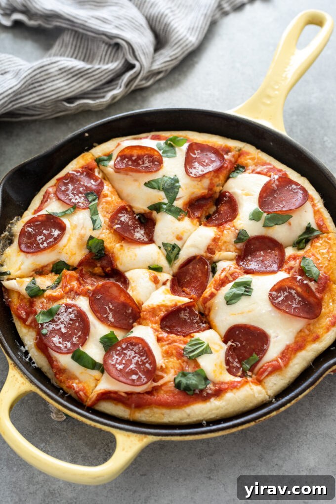 One hour focaccia pizza sliced in a skillet with pepperoni, basil, and melted cheese.