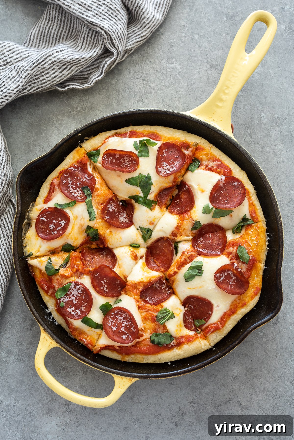 Close-up of focaccia bread pizza topped with pepperoni and fresh basil.