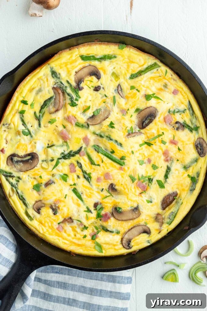 Golden Ham and Cheese Frittata 2 A delicious Ham and Cheese Frittata, golden brown and fluffy, served directly in a cast iron skillet, ready to be sliced.