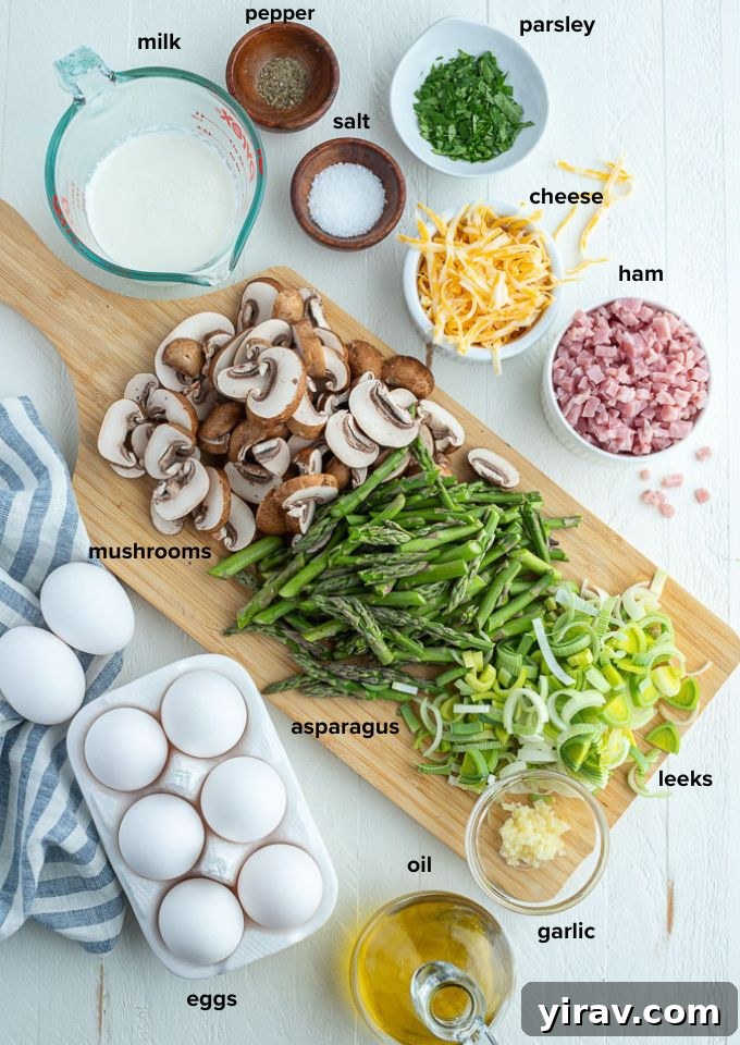 Golden Ham and Cheese Frittata 4 Fresh ingredients laid out for ham and cheese frittata: eggs, diced ham, sliced mushrooms, asparagus, leek, garlic, half-and-half, and shredded cheddar cheese.