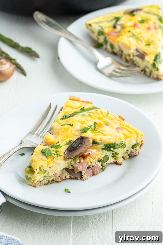 Golden Ham and Cheese Frittata 7 A slice of Ham and Cheese Frittata on a white plate, garnished with fresh parsley, highlighting its fluffy texture.