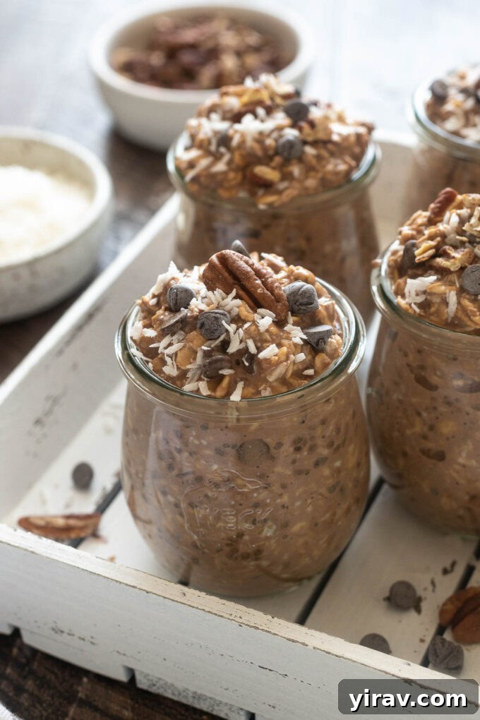 Two jars of German Chocolate Overnight Oats, one with a spoon digging in, topped with coconut and pecans.