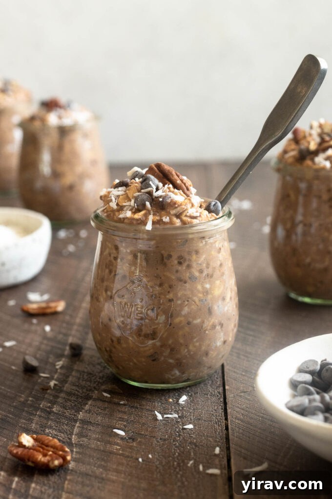 German chocolate overnight oats in a jar with a spoon digging in, showing the creamy texture.
