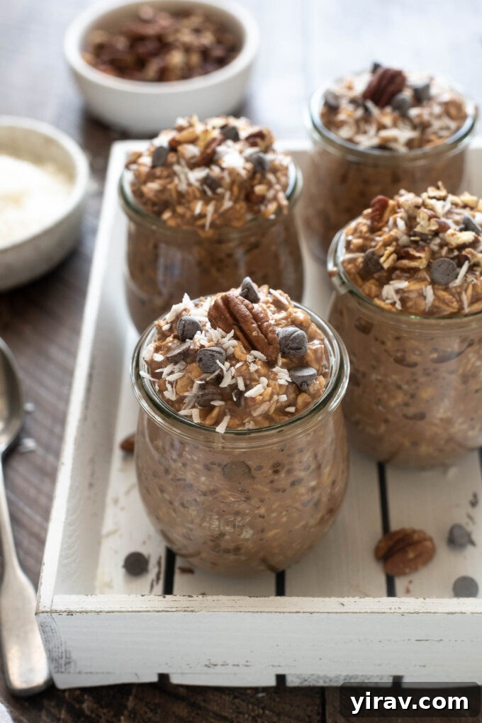 Jars of chocolate overnight oats topped with toasted pecans and shredded coconut, ready to serve.