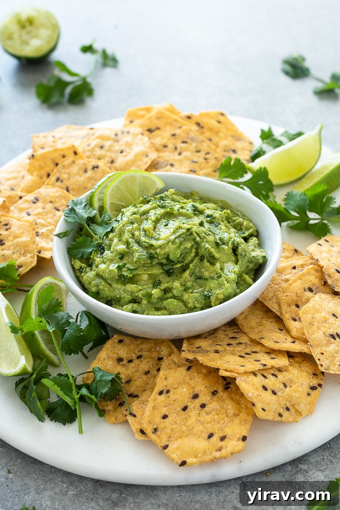 The Ultimate Homemade Guacamole Dip 3 Homemade guacamole in white bowl with lime and cilantro