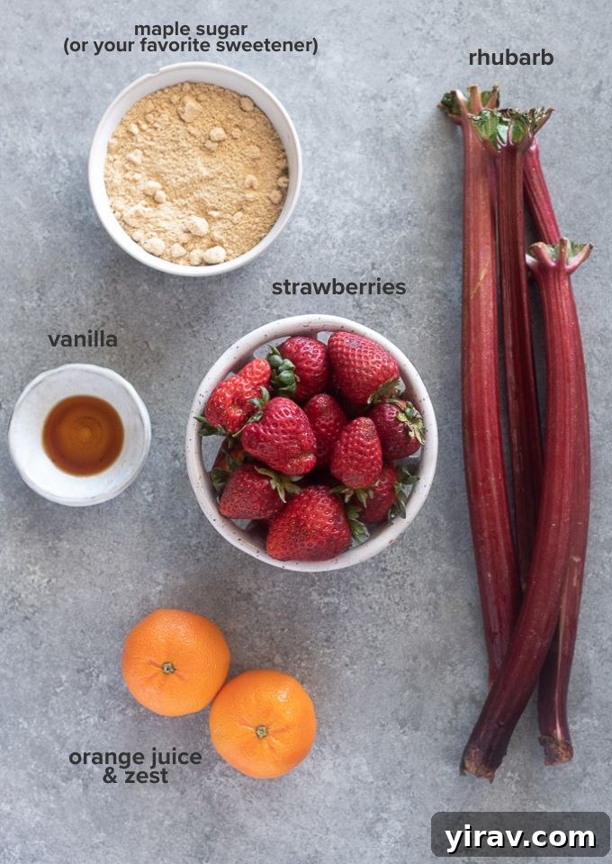 A flat lay showing fresh strawberries, chopped rhubarb, maple sugar, orange zest, and a small bowl of orange juice – the main ingredients for the jam.