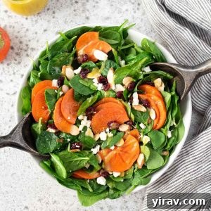 Persimmon salad in a bowl with salad servers, ready to be served