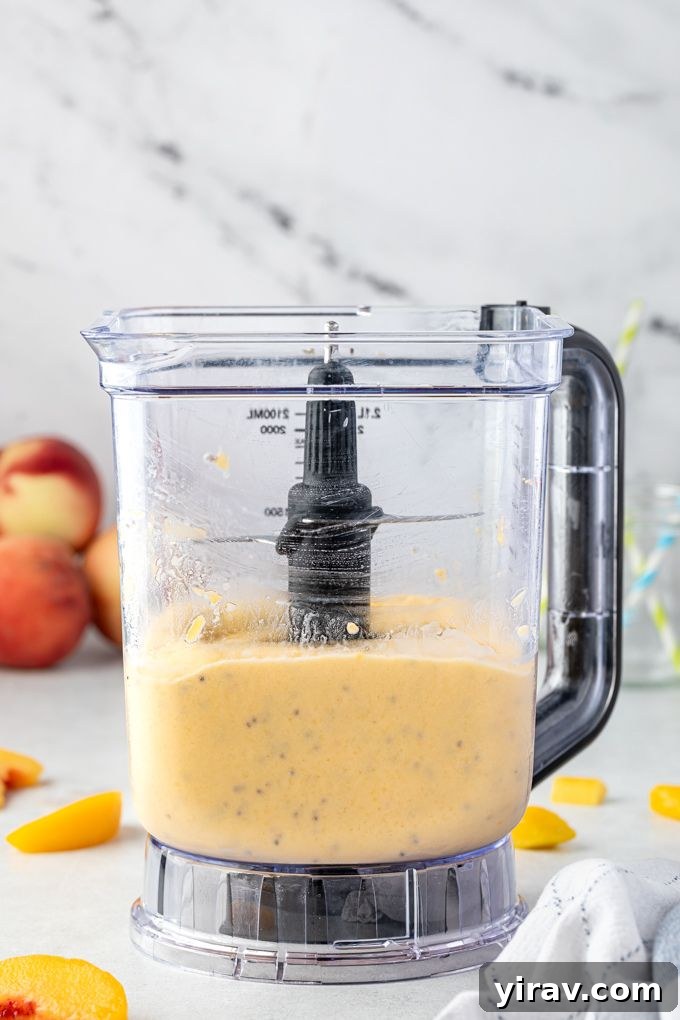 Sunshine Peach Mango Bliss 6 A high-speed blender actively blending peach and mango chunks with liquids, creating a smooth and creamy smoothie mixture.