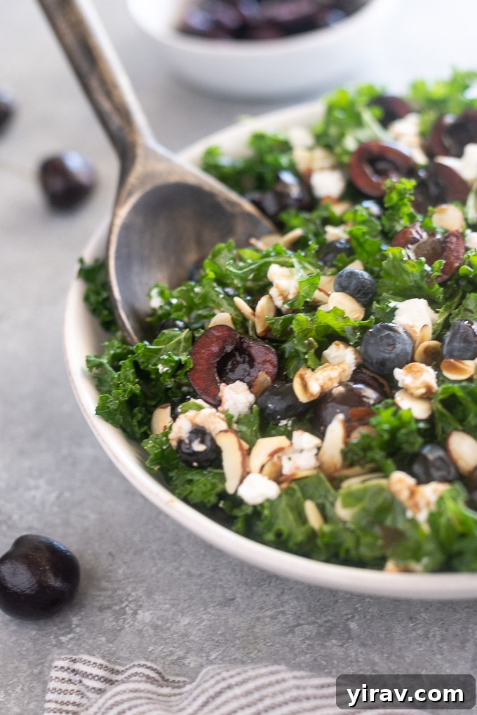 Summer kale salad in a large bowl with serving utensils, ready for a gathering