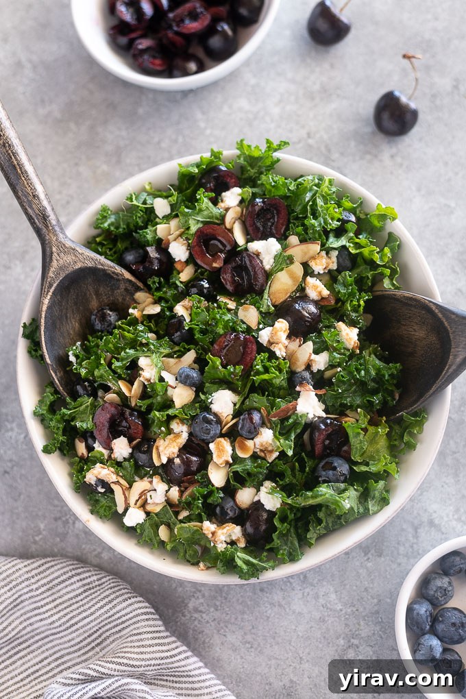Large serving bowl of Kale Cherry Salad with salad servers, ready to be dished out