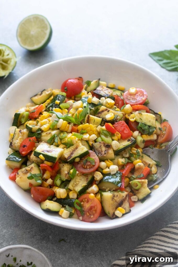 Grilled zucchini and corn salad in a white serving bowl, ready to be served.