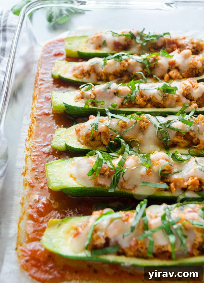 Golden brown Chicken Parmesan Stuffed Zucchini Boats in a baking dish, fresh out of the oven.