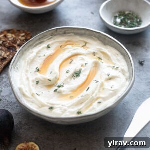 Whipped goat cheese in a bowl topped with honey and thyme.