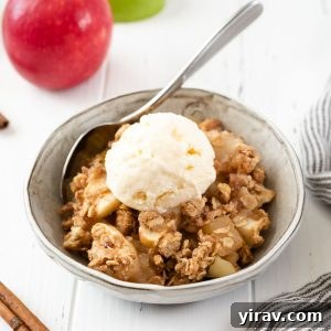 Effortless Apple Crisp 10 A perfectly baked Easy Apple Crisp in a white ceramic dish, with a golden-brown oatmeal topping and a scoop of vanilla ice cream on the side.