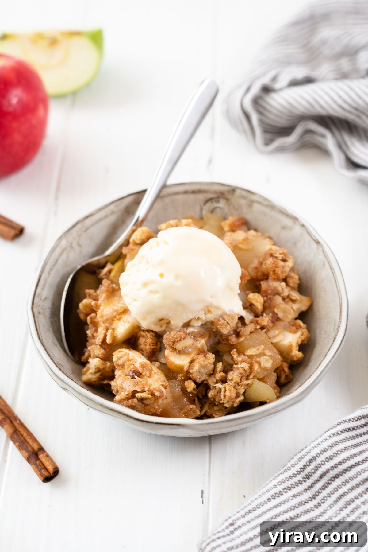 Effortless Apple Crisp 9 A close-up shot of a single serving of apple crisp in a bowl, generously topped with melting vanilla ice cream, highlighting its warm, inviting appearance.