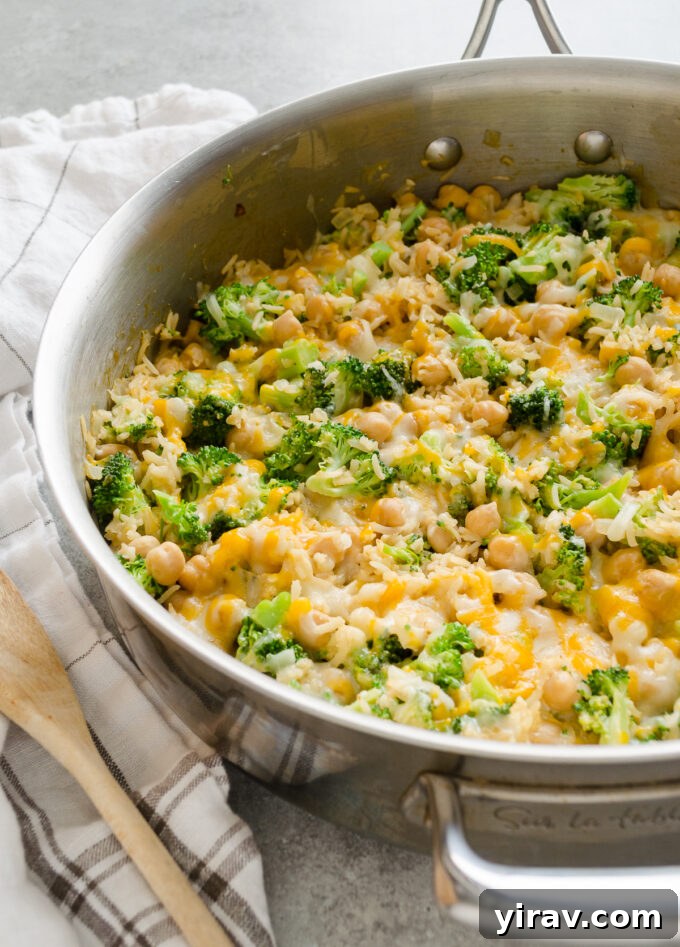 Easy One Pan Chickpea Broccoli Rice Bake 3 Close-up of bubbling vegetarian broccoli and rice casserole, rich with melted cheese, served in a skillet.