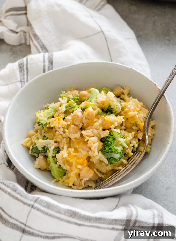 Easy One Pan Chickpea Broccoli Rice Bake 6 Single serving of creamy chickpea broccoli rice casserole in a white bowl, garnished with fresh herbs, ready to eat.