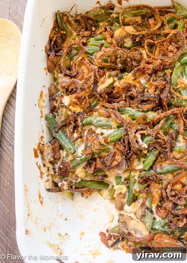 Green bean casserole in baking dish with serving missing, showcasing crispy shallots