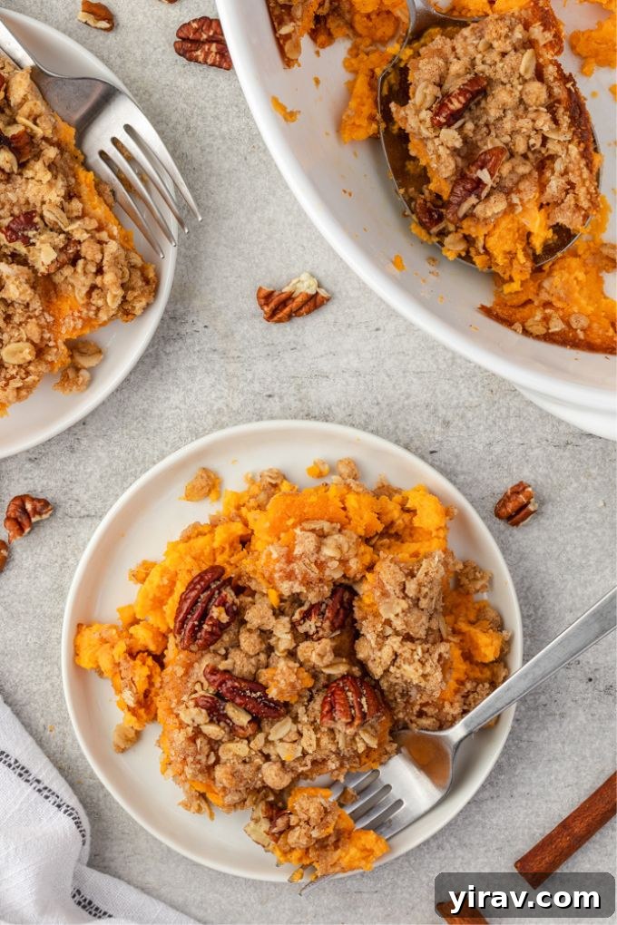 Serving of sweet potato casserole on plates, garnished with fresh herbs, ready for a festive meal