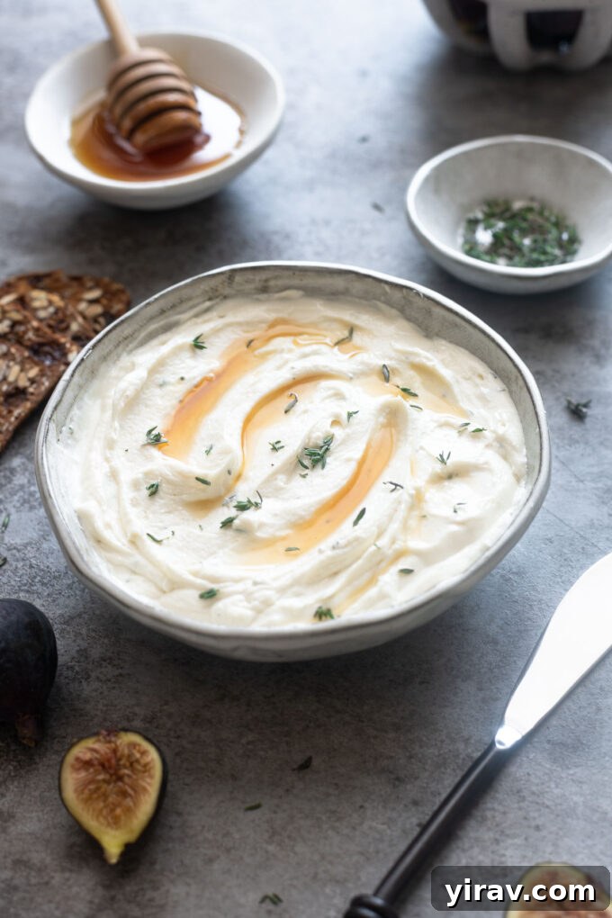Whipped goat cheese in a bowl topped with honey and thyme.