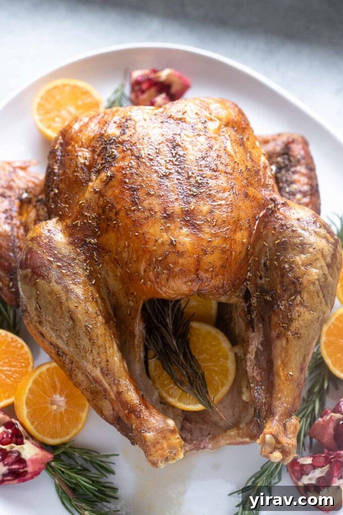 Dry brine turkey on a platter with orange and rosemary.