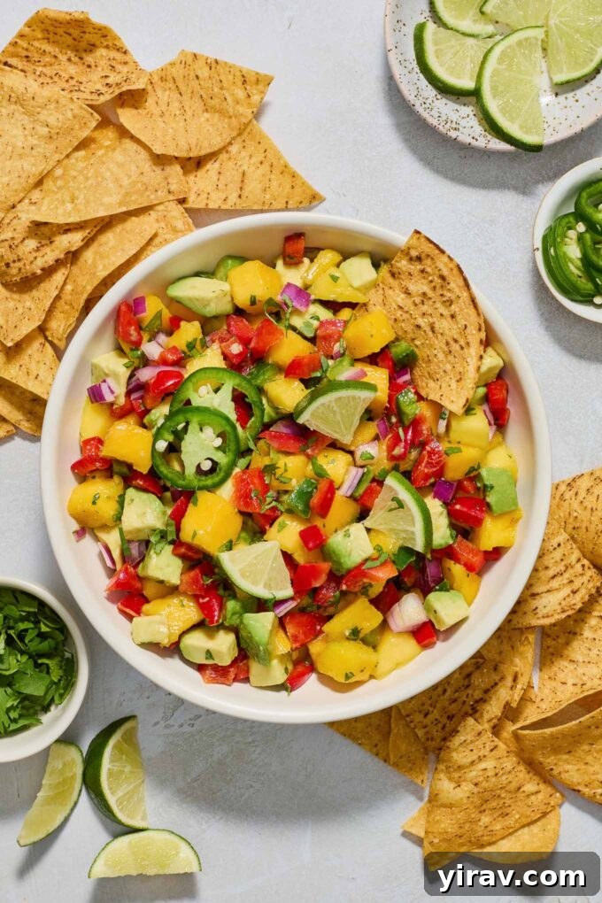 Delicious Mango Avocado Salsa in a bowl, with a tortilla chip dipped in, ready to be enjoyed.
