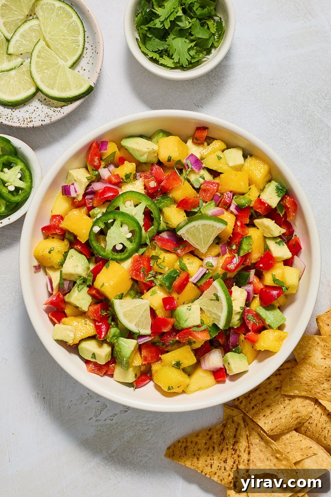 A wide shot of Mango Avocado Salsa surrounded by a generous amount of crispy tortilla chips, perfect for sharing.