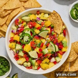 Mango avocado salsa in a bowl with a chip dunked in.