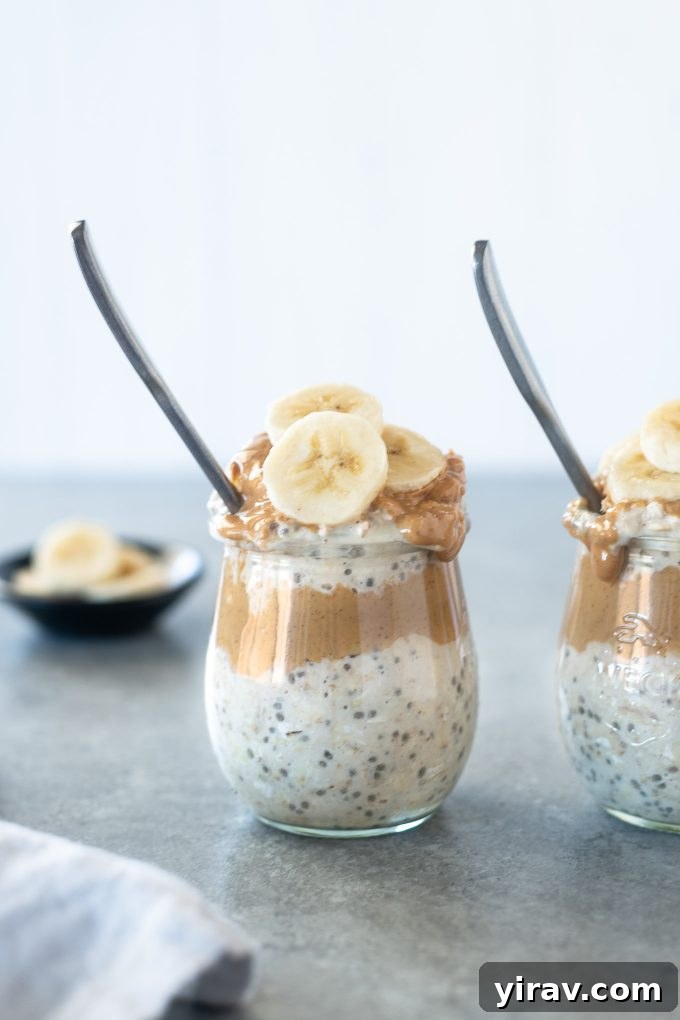 Overnight Peanut Butter Oat Bliss 2 A spoon perfectly buried in a jar of creamy peanut butter overnight oats, topped with sliced bananas and chocolate chips, ready to be enjoyed as a healthy and quick breakfast.
