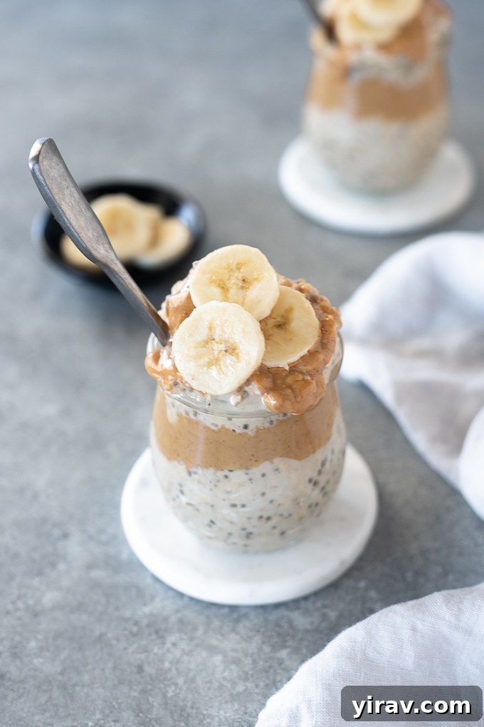 Overnight Peanut Butter Oat Bliss 3 A close-up of a glass jar filled with peanut butter banana overnight oats, topped generously with fresh banana slices and chocolate chips, showcasing a delightful texture.