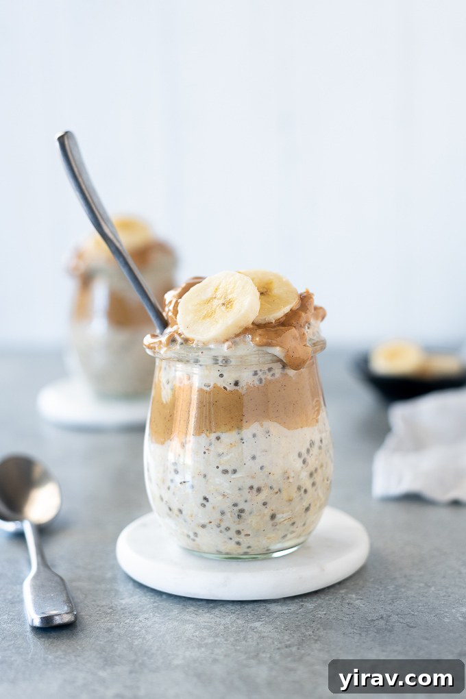 Overnight Peanut Butter Oat Bliss 7 A clear glass jar of peanut butter overnight oats, topped with fresh banana slices, chocolate chips, and a sprig of mint, presented beautifully for a wholesome breakfast.
