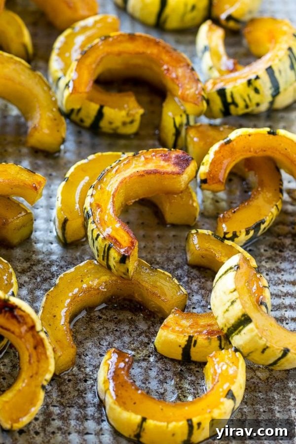 A baking sheet filled with perfectly caramelized Brown Sugar Delicata Squash slices, glistening with a sweet glaze.