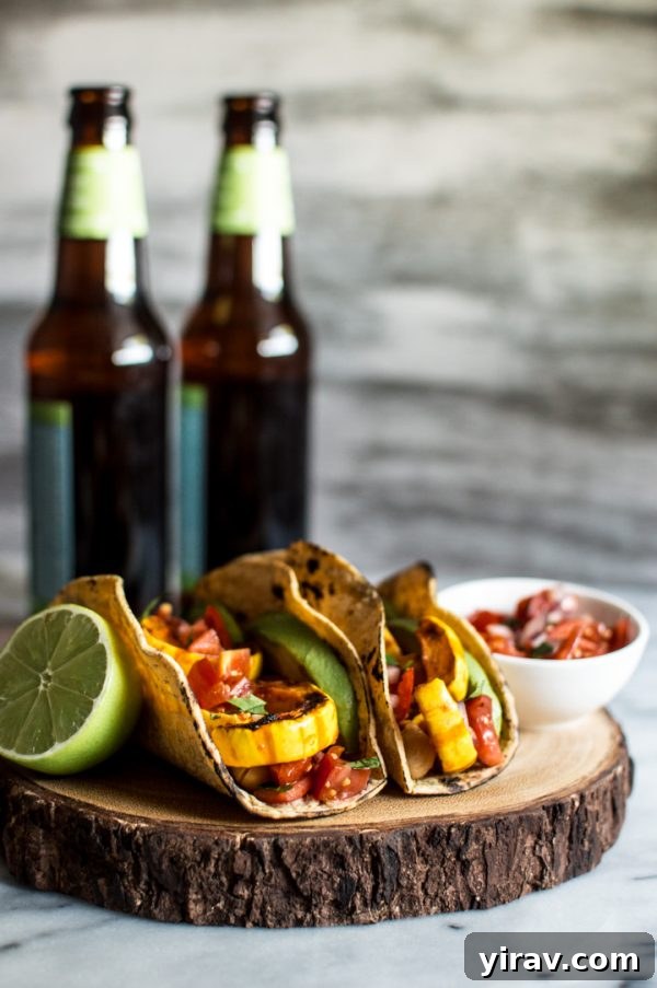 Harissa Miso Delicata Squash Tacos arranged invitingly on a platter, with a refreshing beverage in the background.