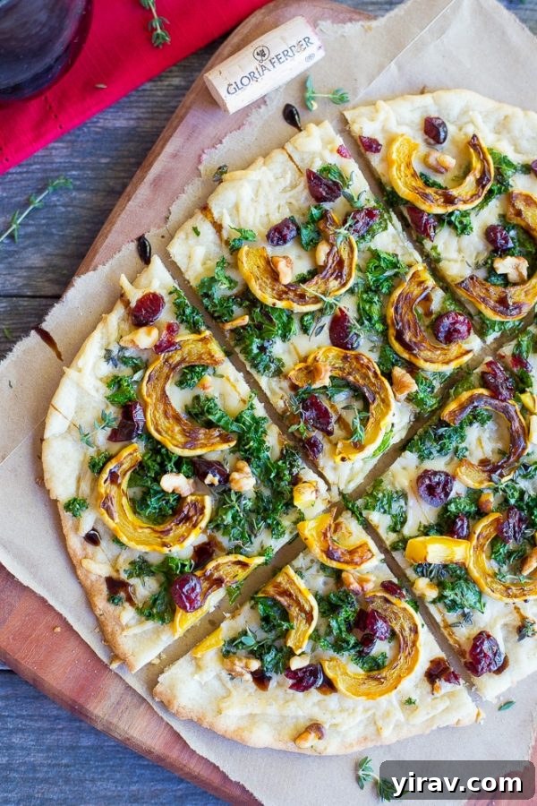 A beautifully prepared delicata squash, kale, and Parmesan flatbread, sliced into square portions, ideal for sharing.