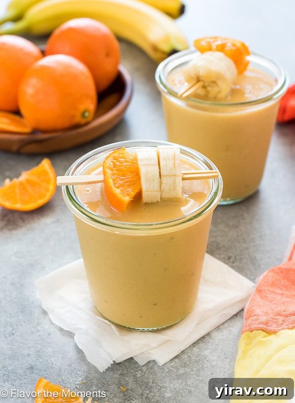 Citrus Cream Dream 2 Vibrant orange creamsicle smoothie in a jar, garnished with fresh orange slice and banana on a toothpick