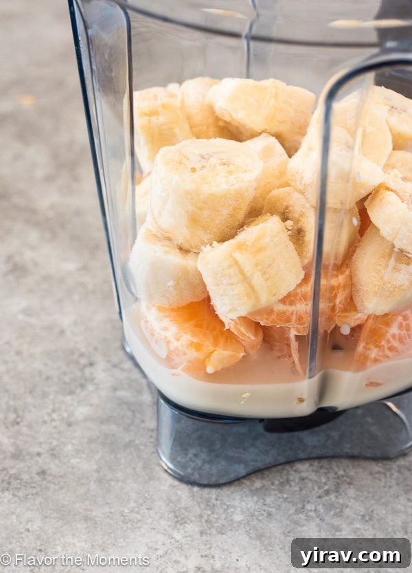 Citrus Cream Dream 4 Blender filled with ingredients for an orange cream smoothie: almond milk, orange segments, and frozen banana chunks