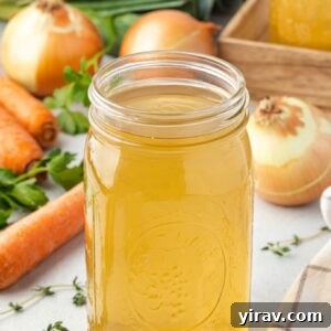 Homemade vegetable broth in a jar surrounded by veggies