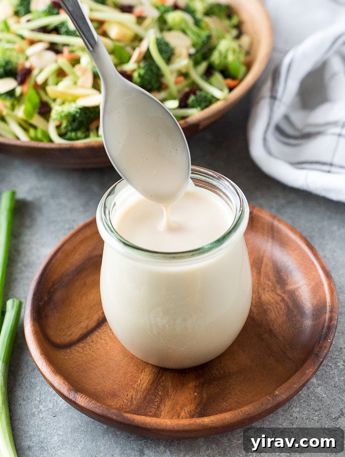 A close-up shot of creamy, homemade coleslaw dressing elegantly presented in a glass jar, highlighting its smooth, inviting texture and readiness to be drizzled over your favorite salads.