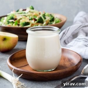 Homemade Coleslaw Dressing in a jar with broccoli salad behind, ideal for a creamy, flavorful side dish.