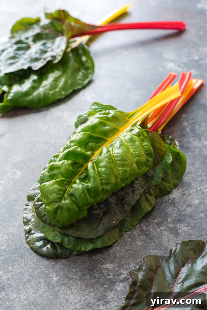A beautifully arranged stack of fresh rainbow Swiss chard leaves, highlighting their vibrant colors and inviting texture.