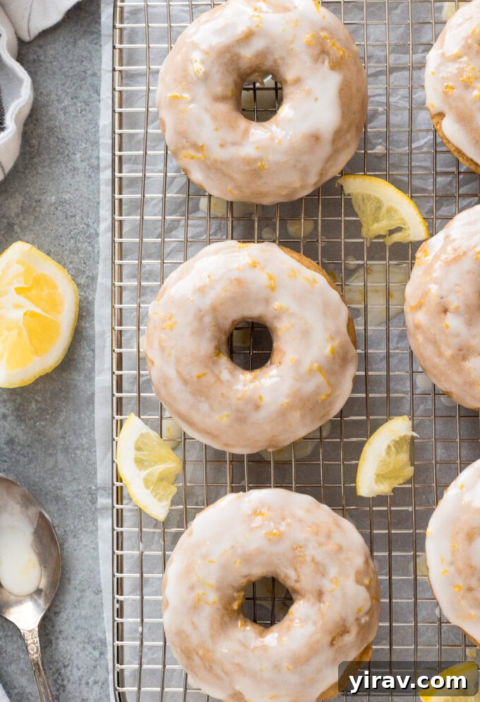Lemon baked donuts with lemon glaze on a wire rack, garnished with fresh lemon zest, ready to be served.