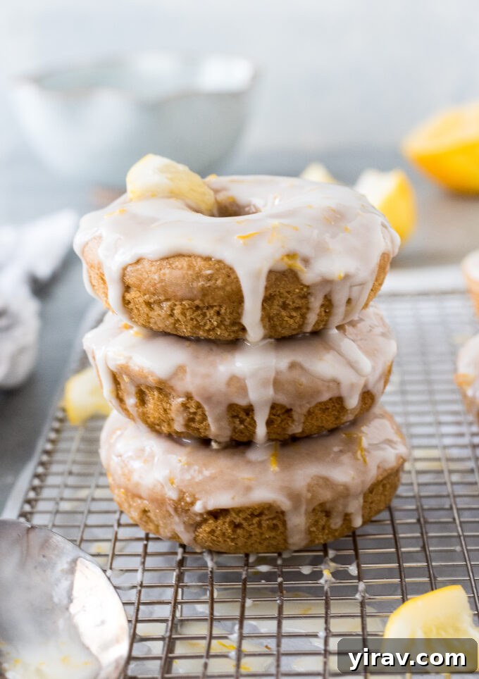 A beautiful stack of glazed lemon donuts on a white plate, ready for serving.