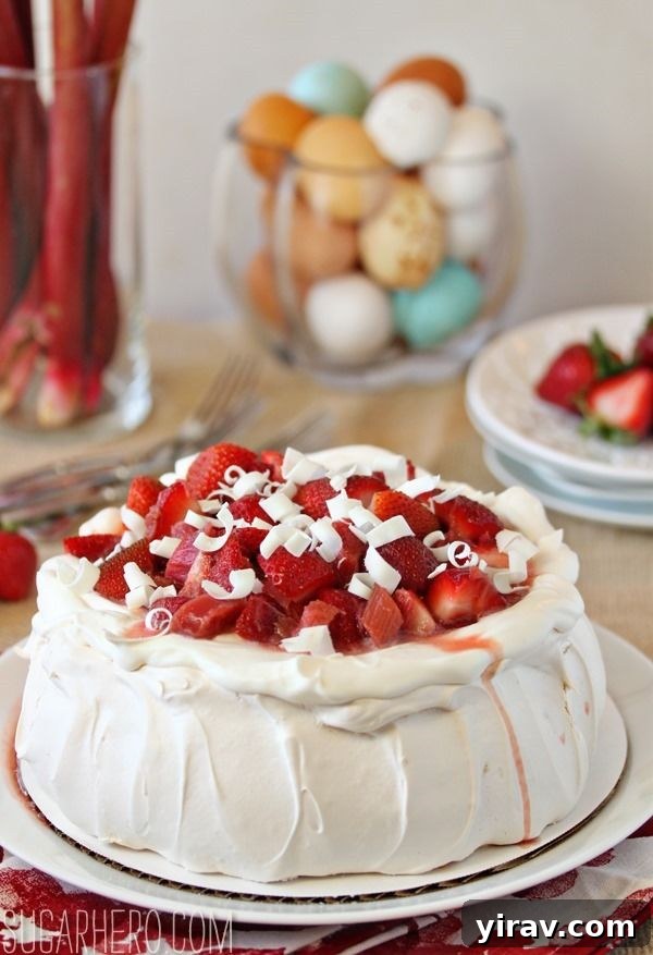 23 Rhubarb Recipes Essential Produce Guide 21 A magnificent Strawberry Rhubarb Pavlova presented on a white platter, generously adorned with fresh fruit.