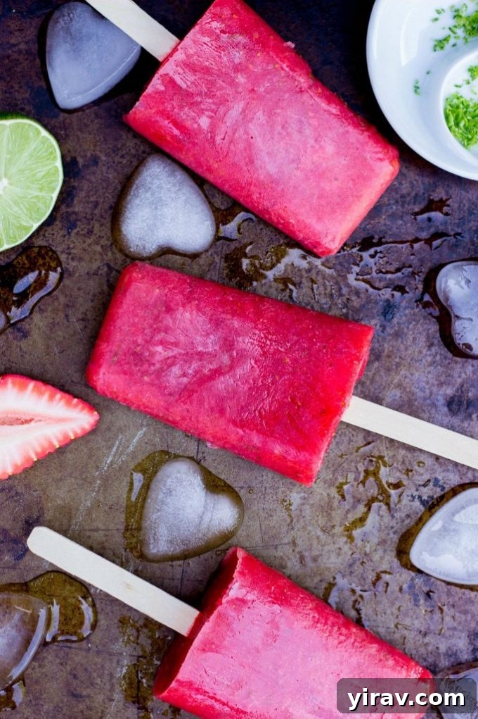 23 Rhubarb Recipes Essential Produce Guide 22 Three refreshing Strawberry Rhubarb Popsicles on a dark background, showcasing their vibrant red and pink hues.