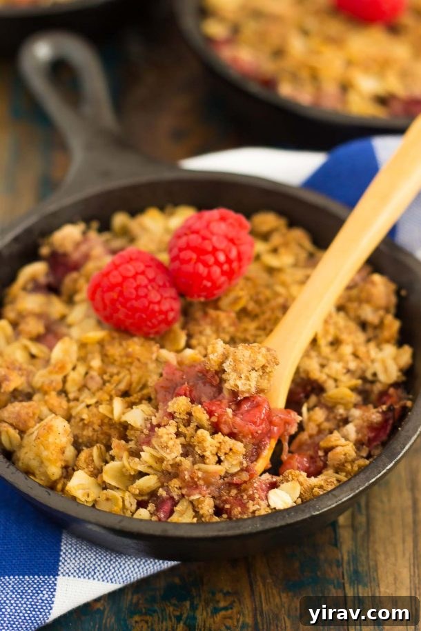 23 Rhubarb Recipes Essential Produce Guide 23 A mini Raspberry Rhubarb Crisp served in a small cast iron skillet, with a wooden spoon resting inside, ready to be devoured.