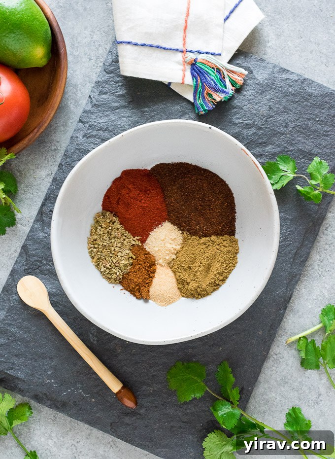 Various individual spices, including chili powder, cumin, paprika, and oregano, neatly arranged in a bowl, illustrating the fresh components of a homemade taco seasoning blend.