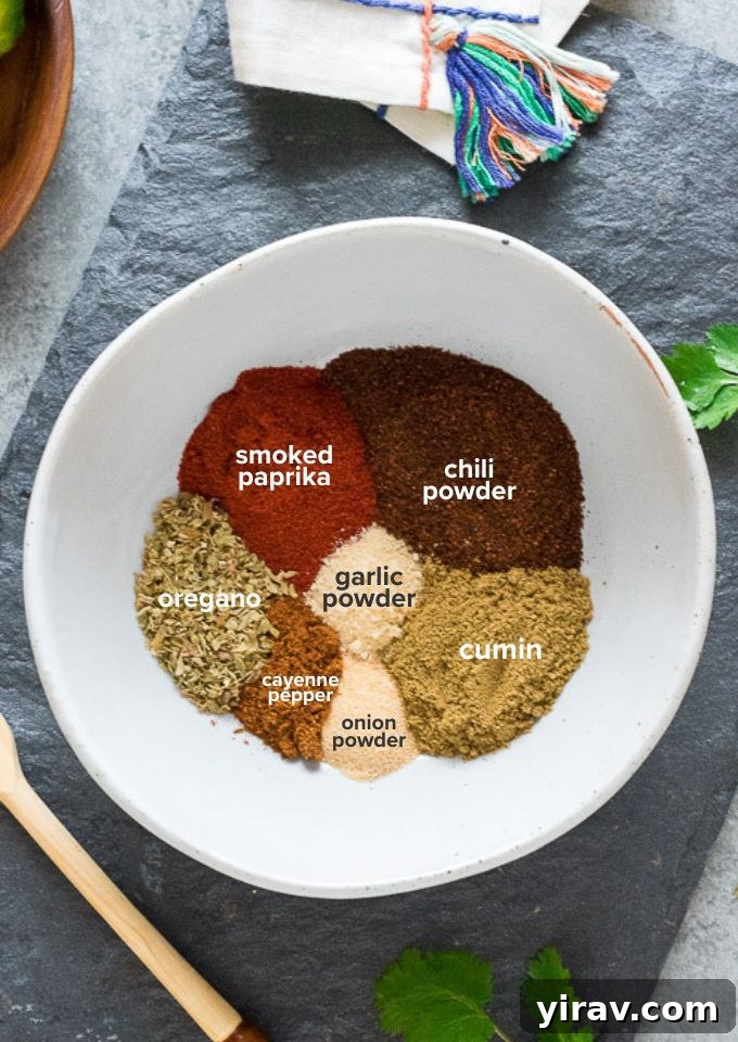 Labeled individual spices, including chili powder, cumin, smoked paprika, garlic powder, onion powder, dried oregano, cayenne pepper, and salt, laid out before mixing to create a homemade taco seasoning.